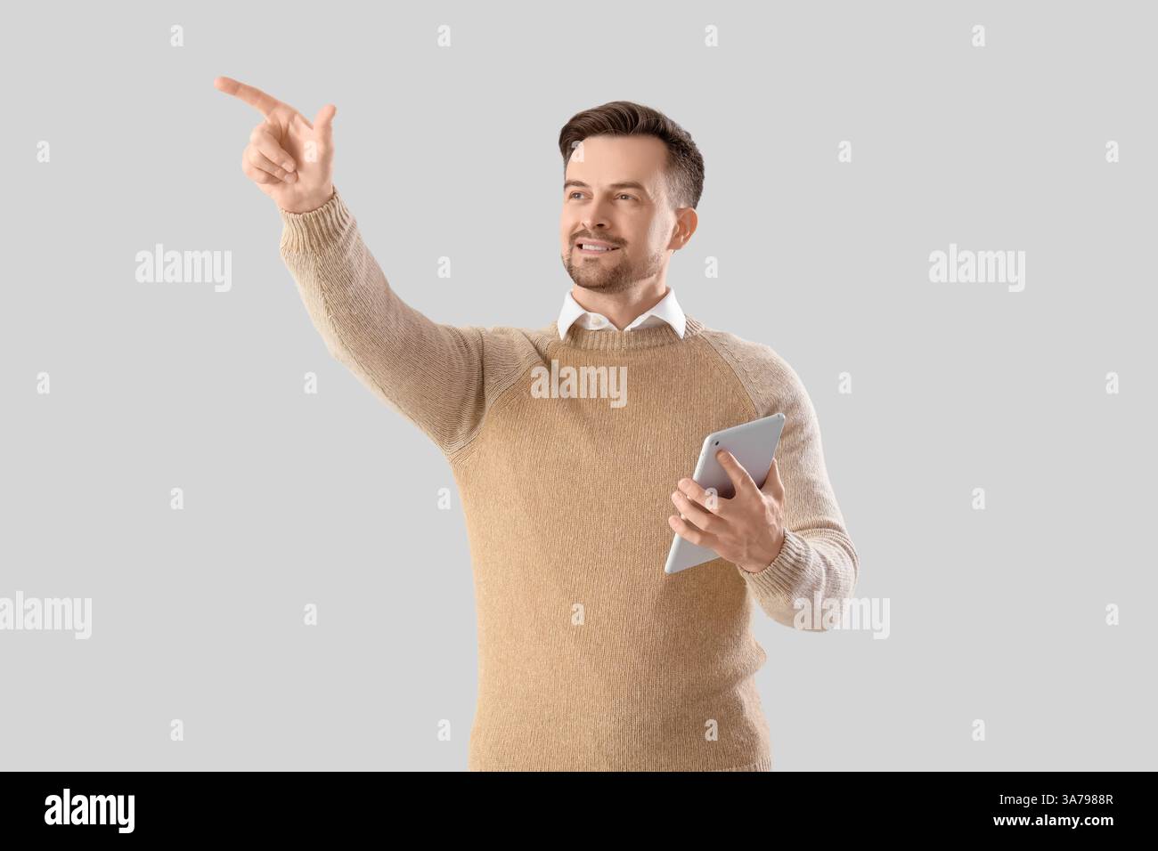 Young businessman with tablet computer using virtual screen on light background Stock Photo