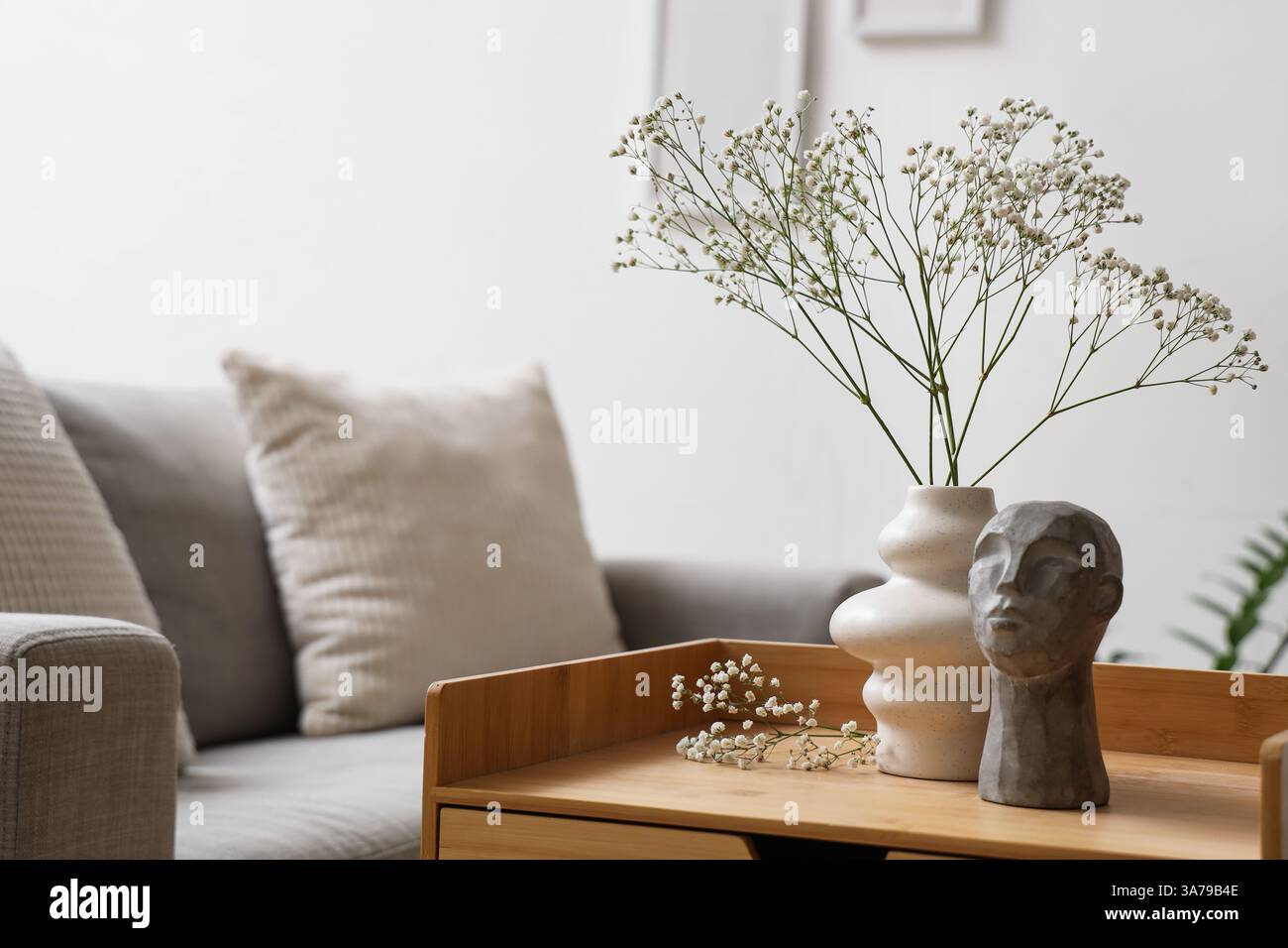 Gypsophila flowers in vase and stone human head on bedside table in ...