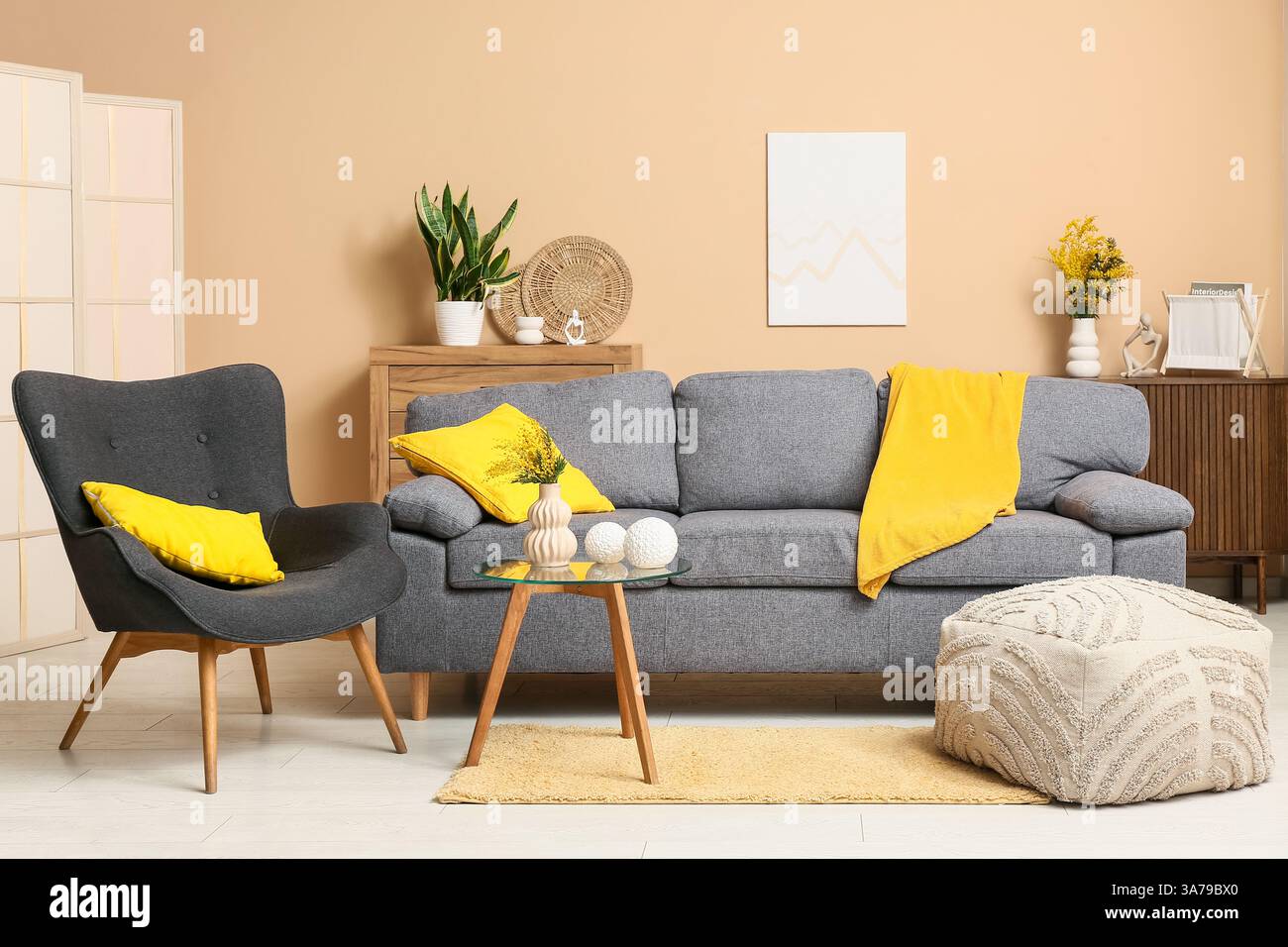 Interior of living room with sofa, armchair and mimosa flowers in vase ...