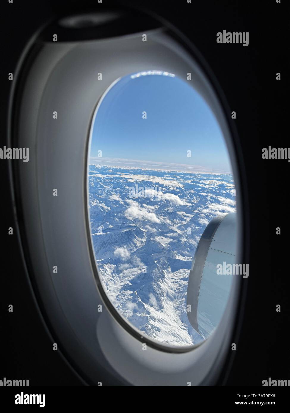 Holiday snap of the snowy mountains above the Austrian Alps taken through an aeroplane window during flight. - Smartphone Captured Stock Image