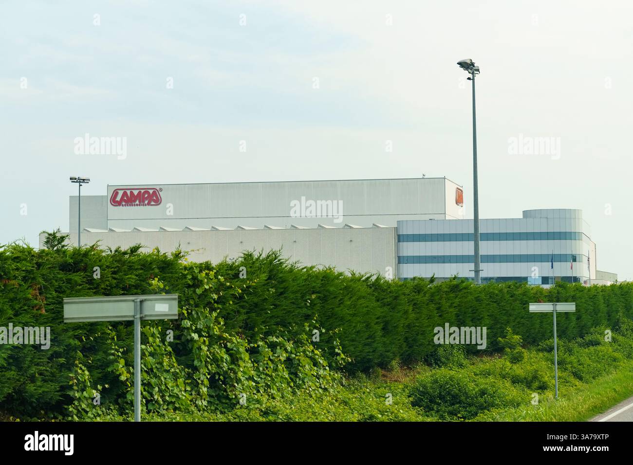 Reggio Emilia, Italy - June 14, 2023:A contemporary industrial building rises amidst lush greenery under clear blue skies, reflecting innovation and p Stock Photo