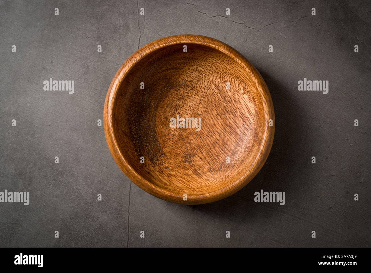 Top view of empty wooden nuts bowl on dark grey stone table Stock Photo