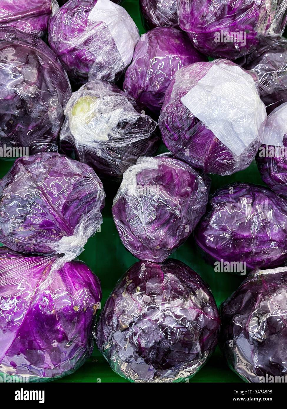 Pile ripe red cabbages wrapped in plastic wrap displayed on supermarket - Smartphone Captured Stock Image