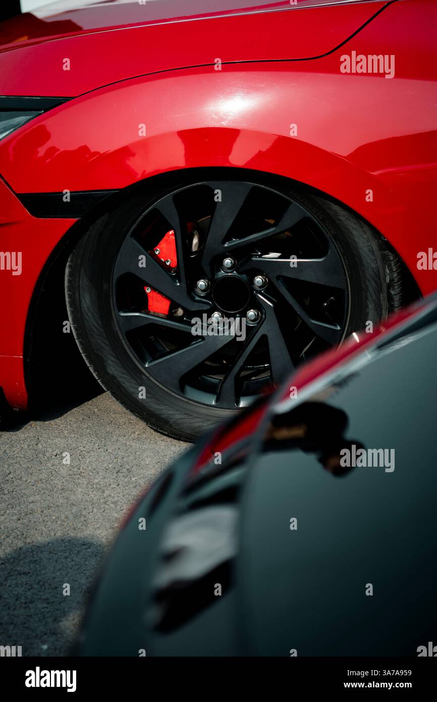 A close-up of a vibrant red sports car wheel featuring a beautifully crafted alloy rim. Perfect for showcasing luxury automotive design, performance b Stock Photo