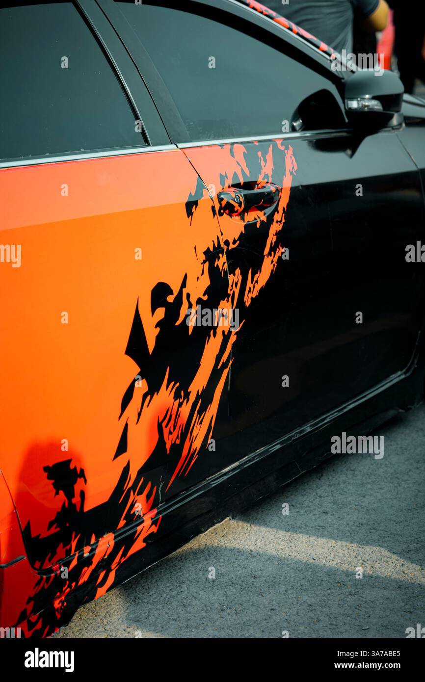 A sleek sports car in orange and black, adorned with eye-catching graphic stickers that emphasize speed and attitude. Ideal for automotive enthusiasts Stock Photo