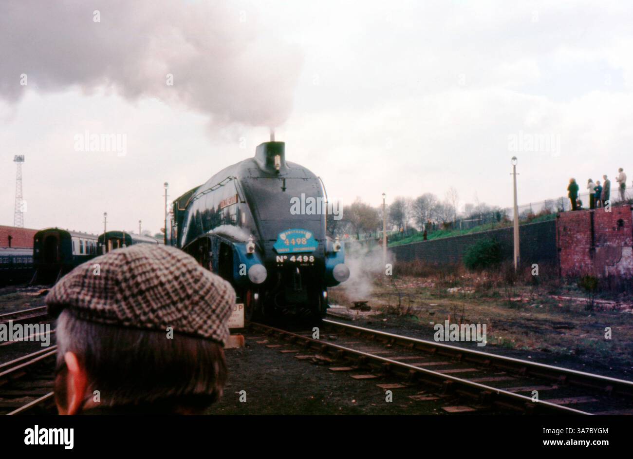 Original 1960s 35mm slide film photo showcasing the iconic LNER Class A4 steam locomotive No. 4498 'Sir Nigel Gresley'. Captured during a rail heritage event, the images feature the streamlined blue engine surrounded by steam, spectators, and vintage carriages, evoking the golden age of British steam railways. Stock Photo