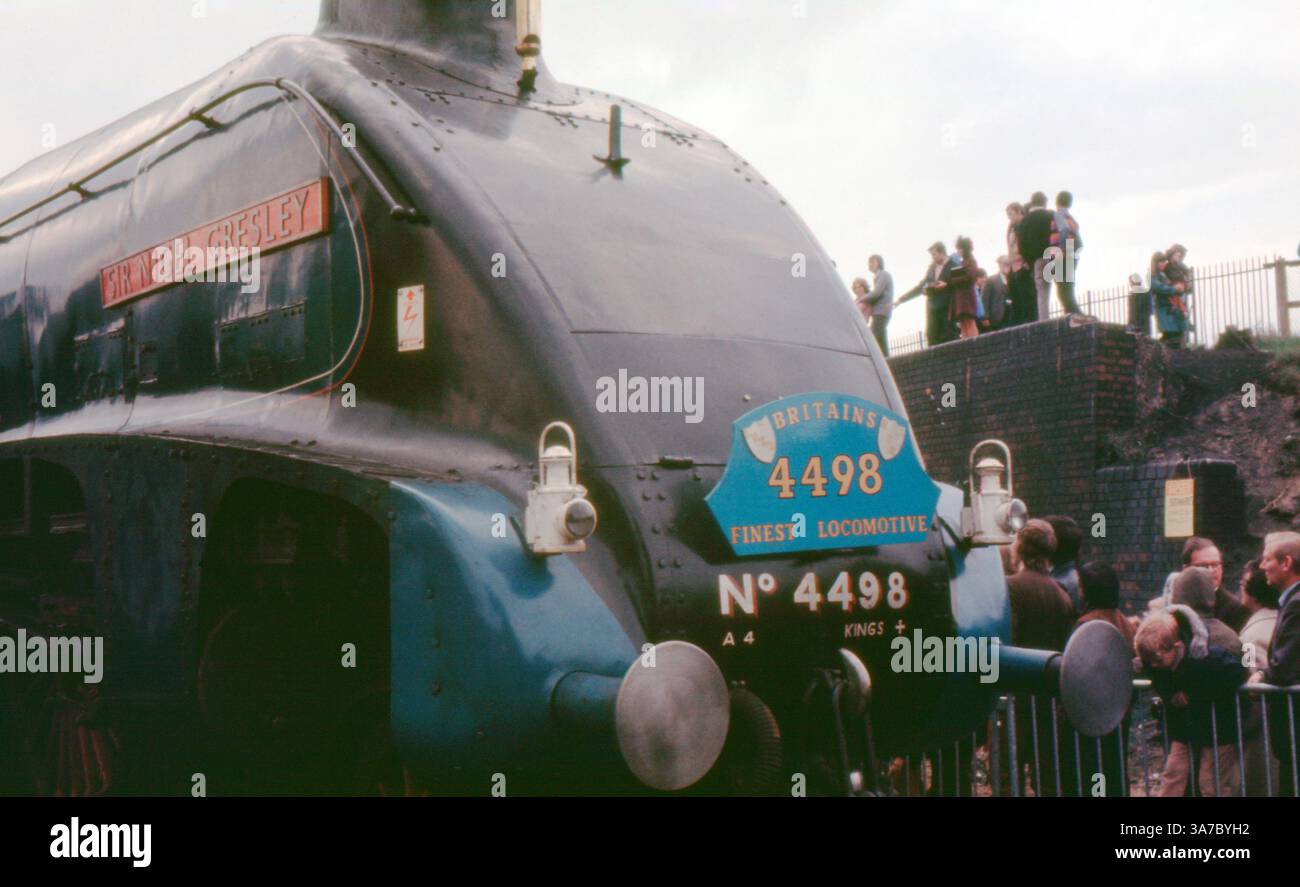 Original 1960s 35mm slide film photo showcasing the iconic LNER Class A4 steam locomotive No. 4498 'Sir Nigel Gresley'. Captured during a rail heritage event, the images feature the streamlined blue engine surrounded by steam, spectators, and vintage carriages, evoking the golden age of British steam railways. Stock Photo