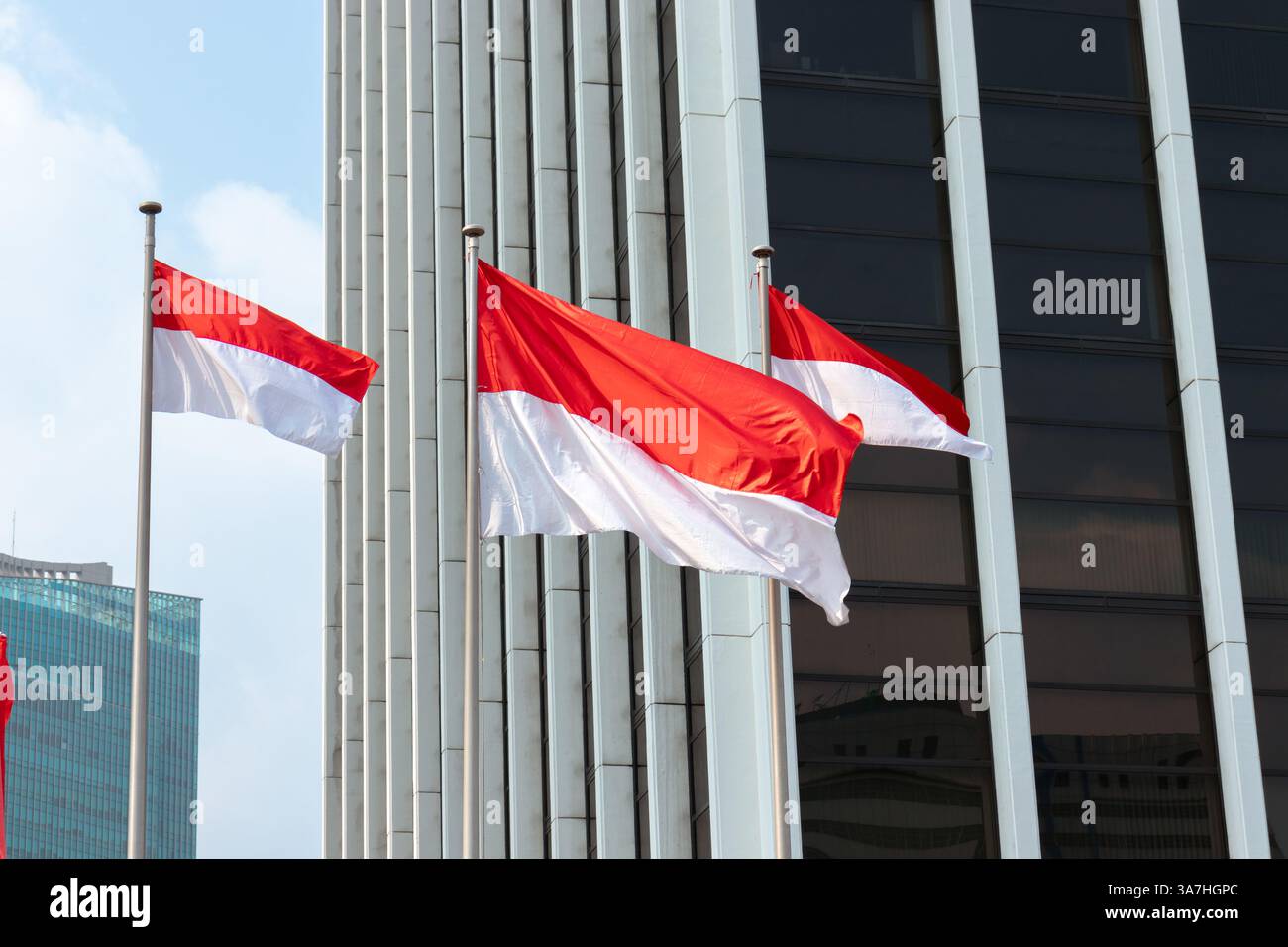 Indonesian flags waving in the wind in front of modern office building ...