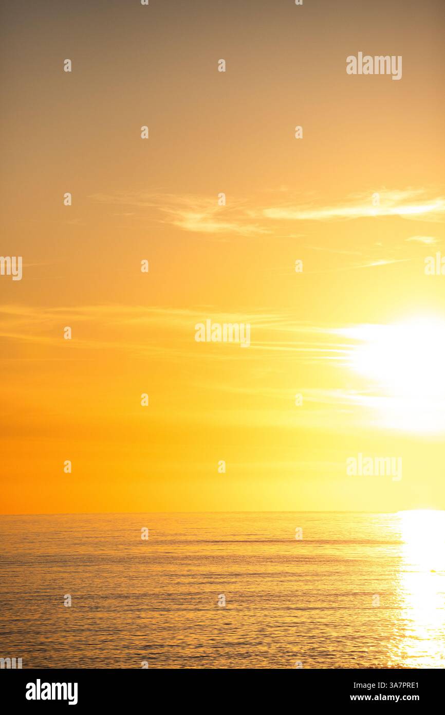 A golden sunset over the calm sea in Albania, with warm hues blending ...