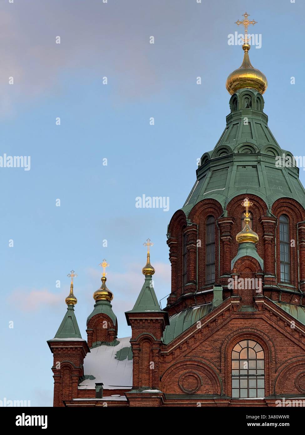 A red - brick church with green domes and golden onion - shaped tops against a blue sky, adorned with crosses. - Smartphone Captured Stock Image