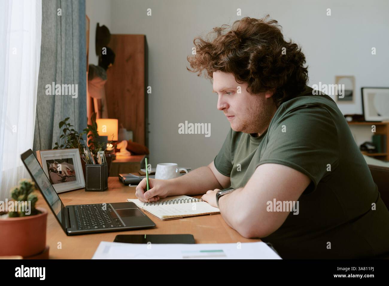 Man Working from Home Using Laptop on Wooden Desk Stock Photo
