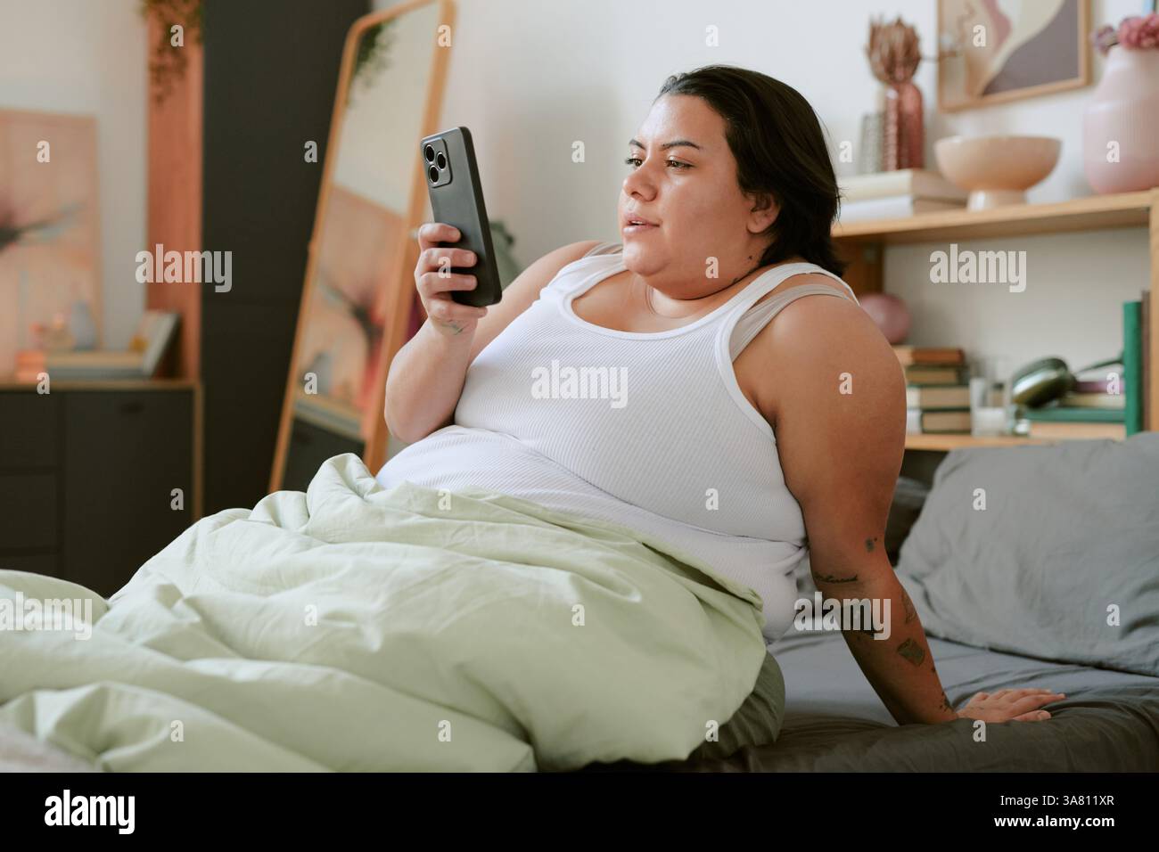 Woman Relaxing on Bed While Using Smartphone Stock Photo