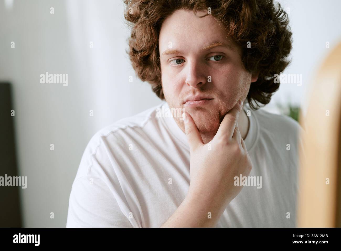 Portrait of Pensive Young Man Touching His Chin Stock Photo