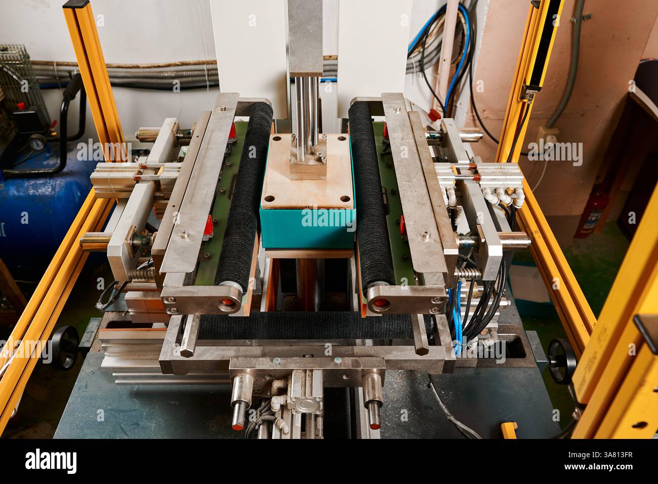 Innovative semi-automatic machine expertly wrapping rectangular boxes in a bustling packaging facility Stock Photo