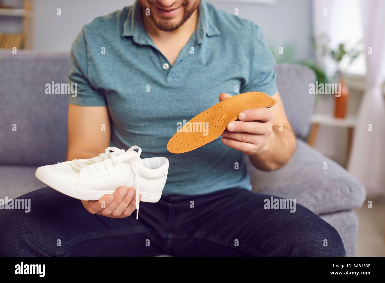 Man Inserting Orthopedic Insole Into Shoe At Home Stock Photo