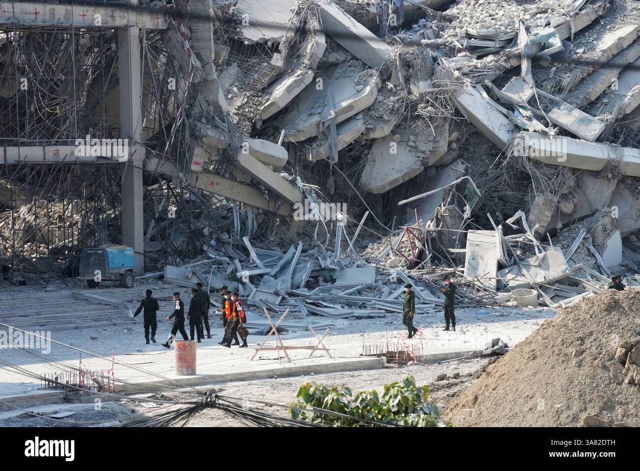 Rescuers walk at the site of a high-rise building under construction ...