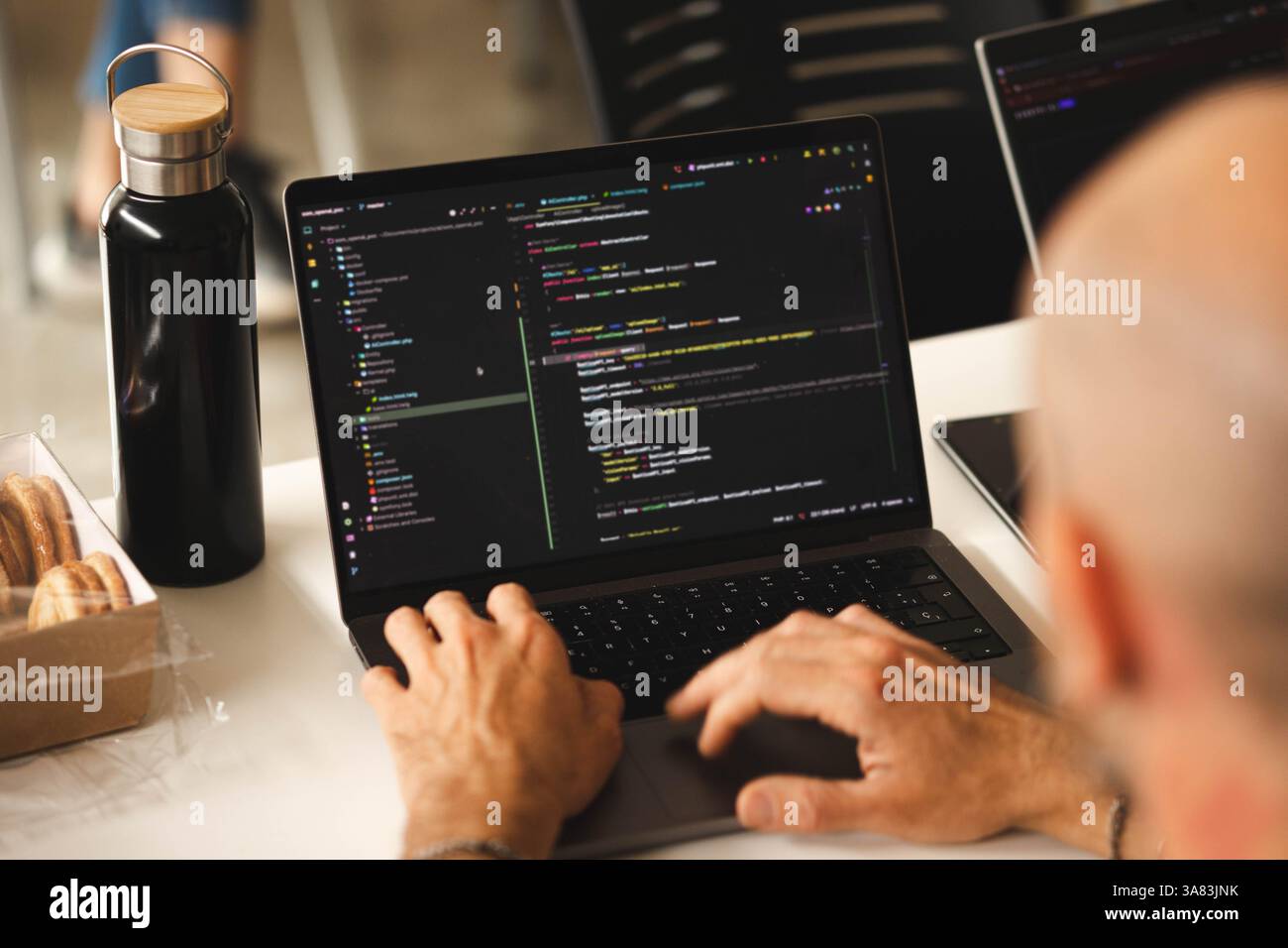 A close-up of a laptop while the hands of a man are writing code Stock Photo