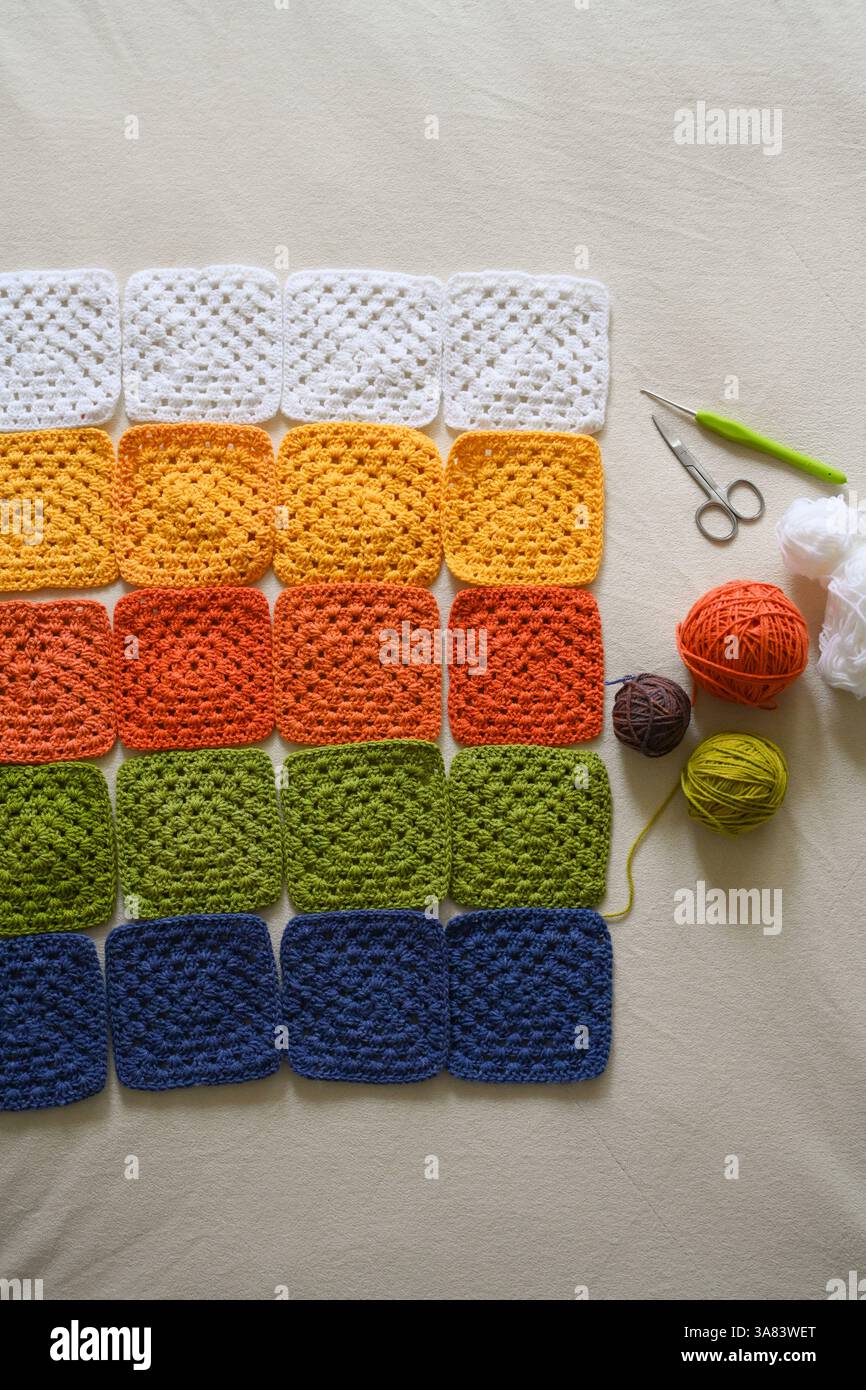 Crocheted squares blanket in making, multi-colored granny square Stock Photo