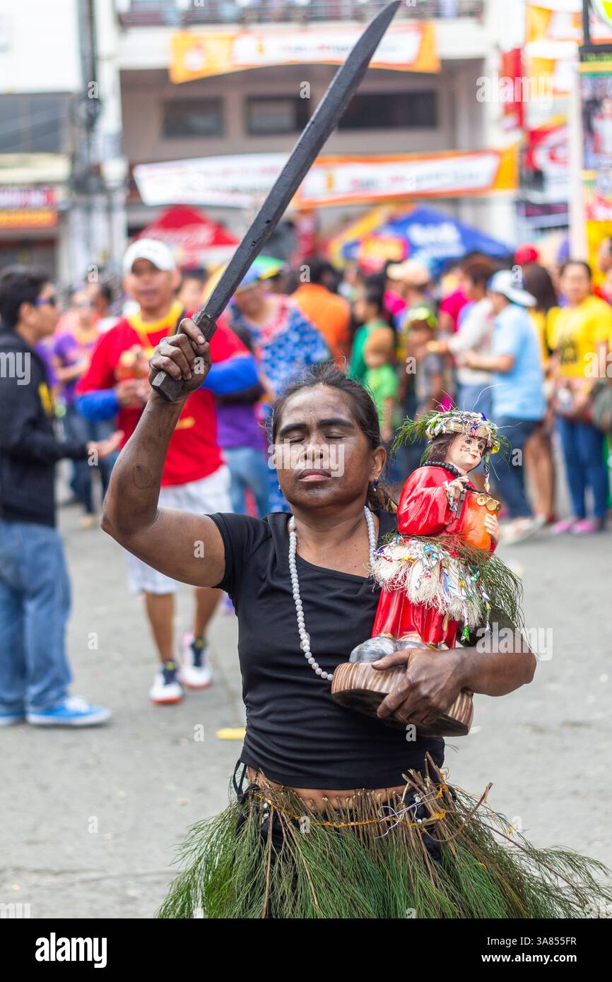 Woman in indigenous costume holding a bladed weapon and an image of Sto ...