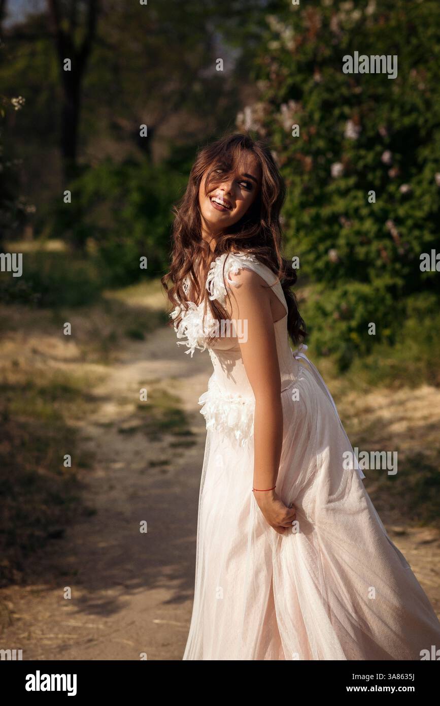 Stunning bride gracefully poses in a spring park, among blossoming trees. exuding elegance, Stock Photo