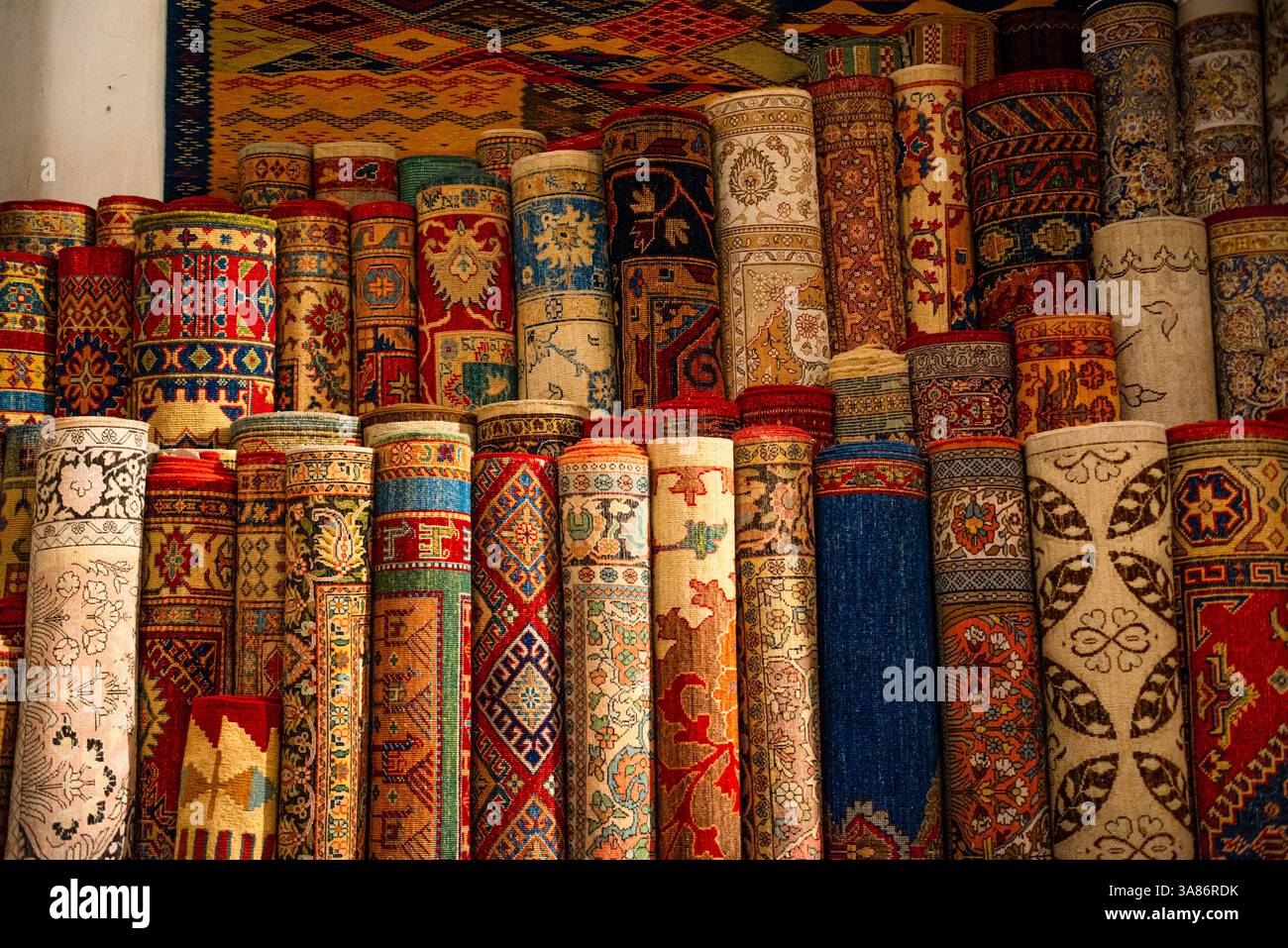 Stacks of vibrant handwoven Moroccan rugs and carpets displayed in a traditional shop in Fes, Morocco Stock Photo