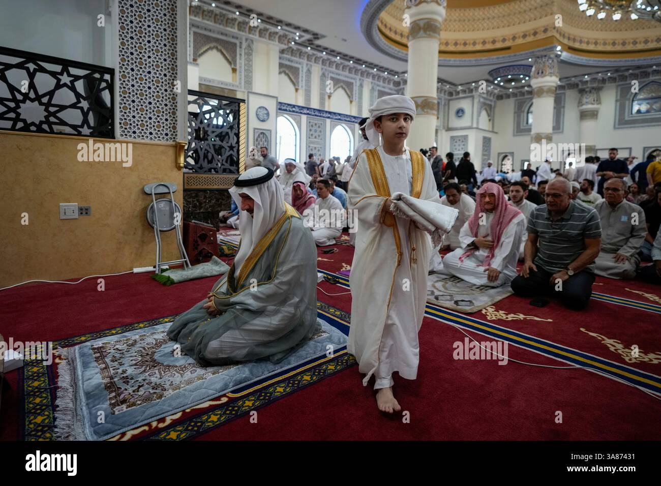 A young Emirati boy carries a praying rug after the Friday prayers of ...