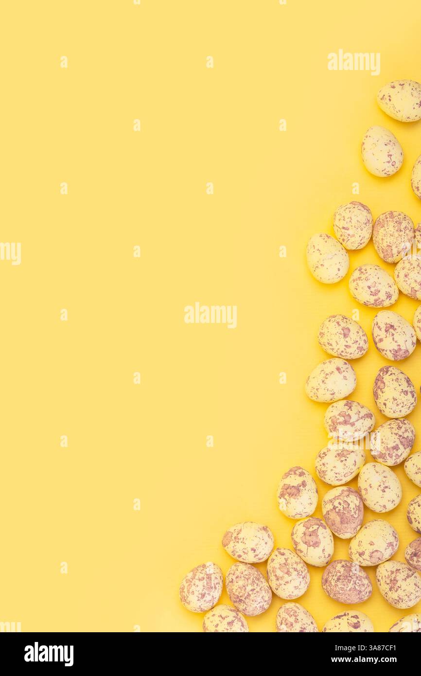 Vertical banner with small easter eggs on yellow background with empty space Stock Photo
