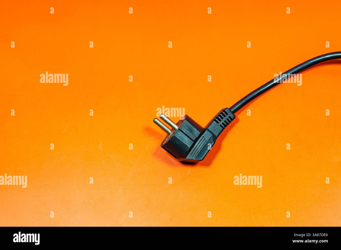 Black plug cable on an orange surface. Stock Photo