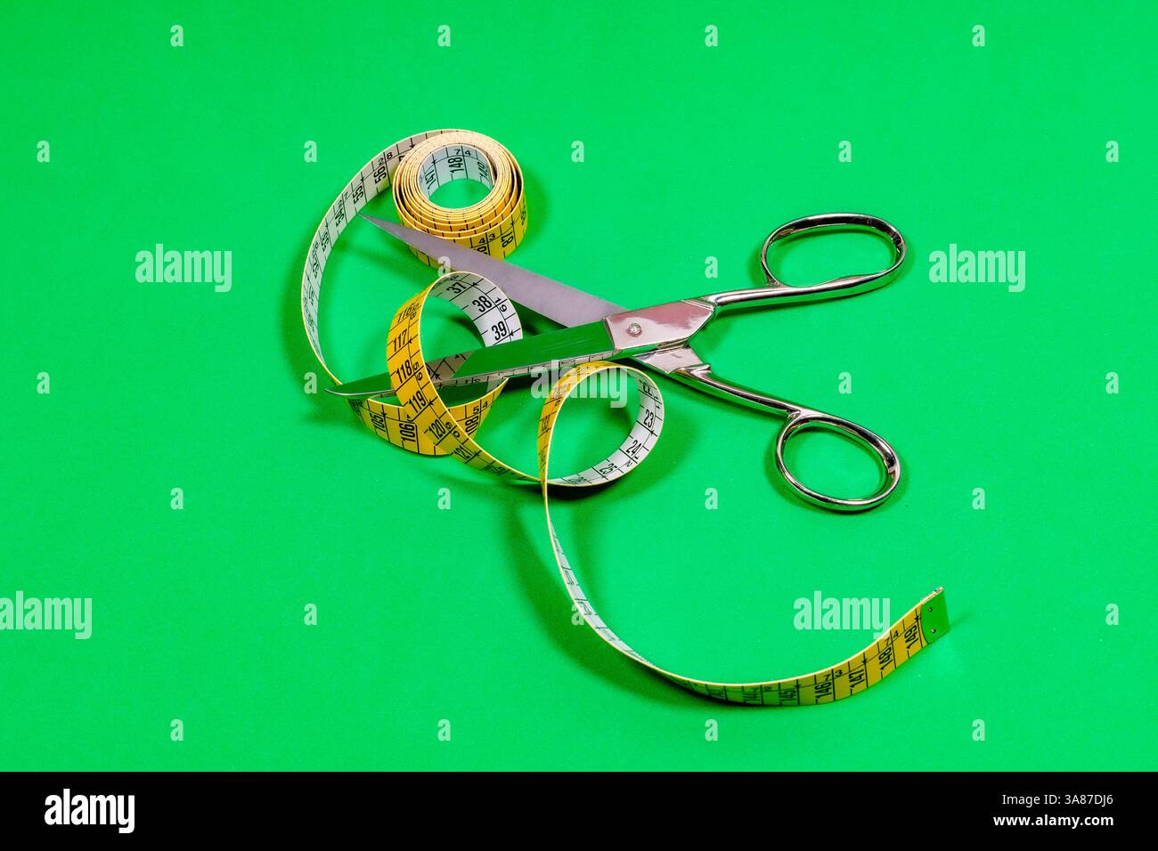 Tape measure and sharp tailor's scissors, placed on the table. Stock Photo