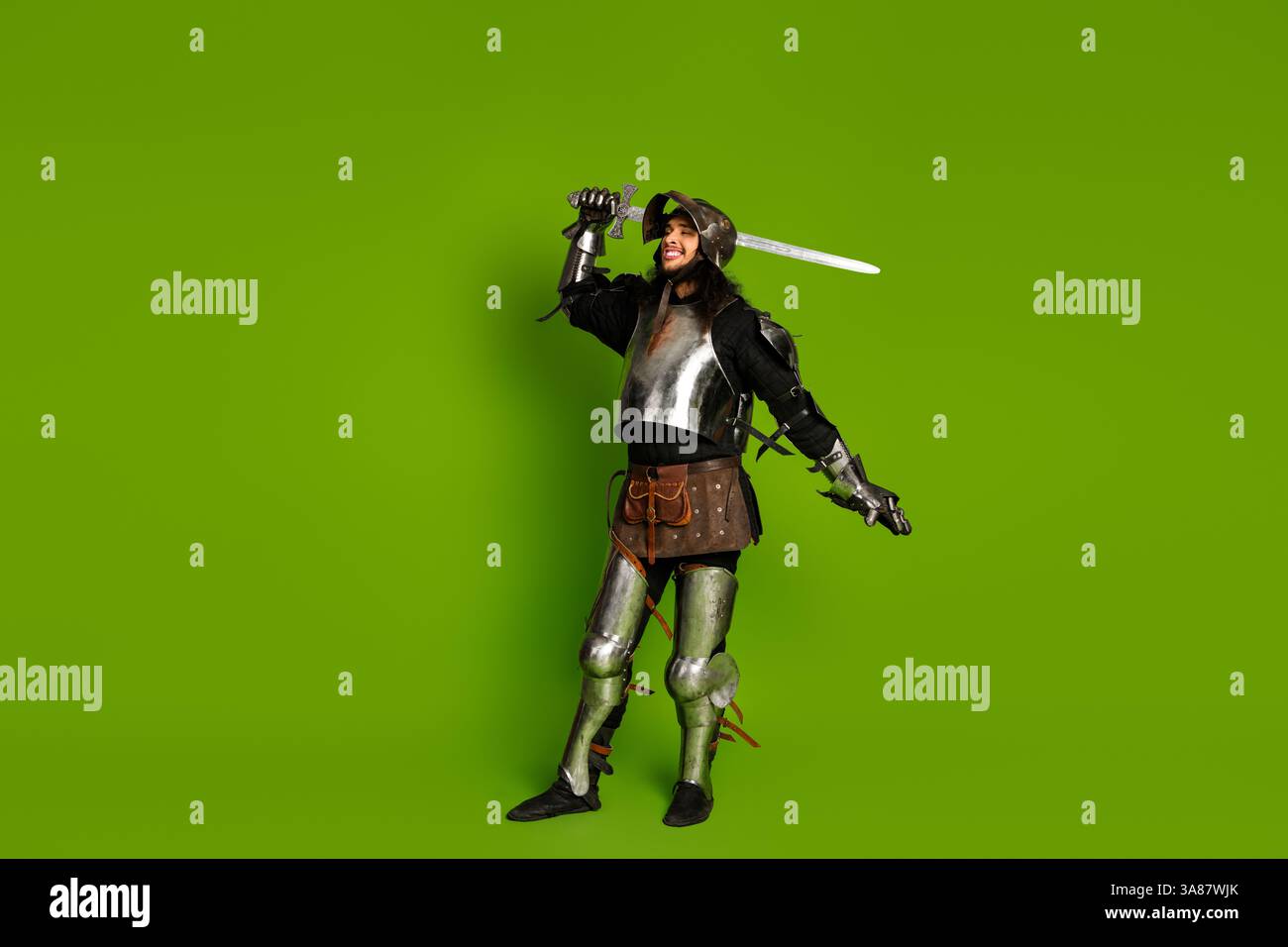 Medieval knight in full armor holding a sword on a vibrant green ...