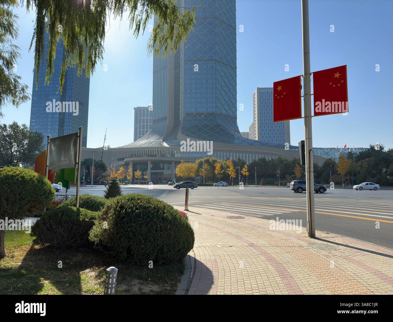 Modern cityscape with skyscrapers, China flags, and a vibrant blue sky.Yinchuan, China - Smartphone Captured Stock Image
