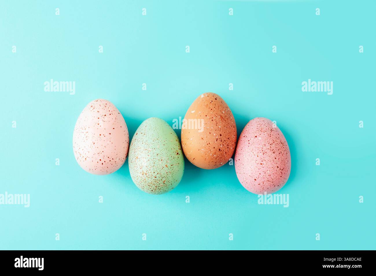 Speckled pastel Easter eggs on turquoise background. Top view, flat lay. Stock Photo
