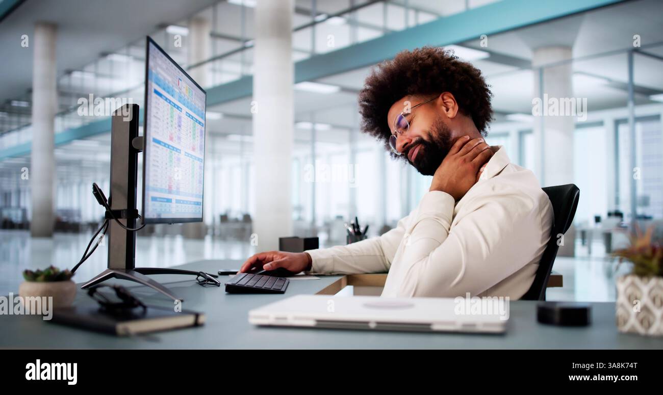 Stretches When Using A Computer African American businessman stretches muscles at workstation computer ...
