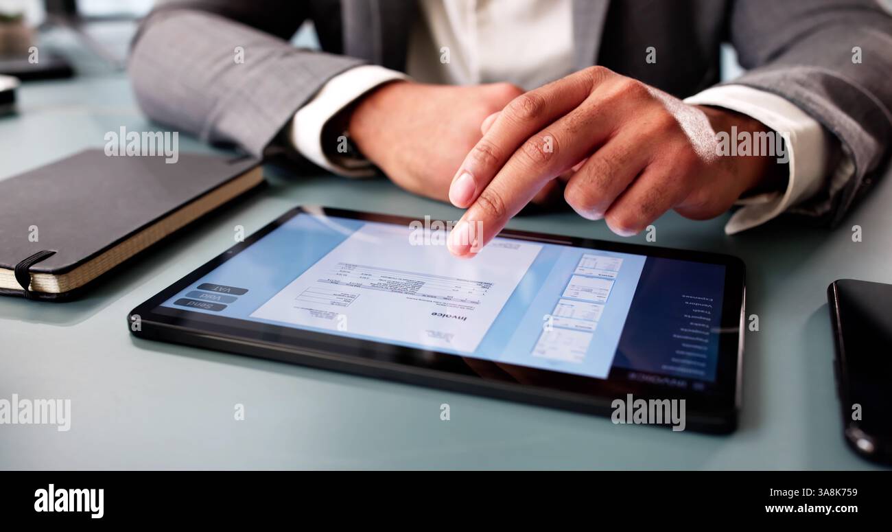 Young accountant calculating expenses, preparing electronic invoice on computer software. Stock Photo