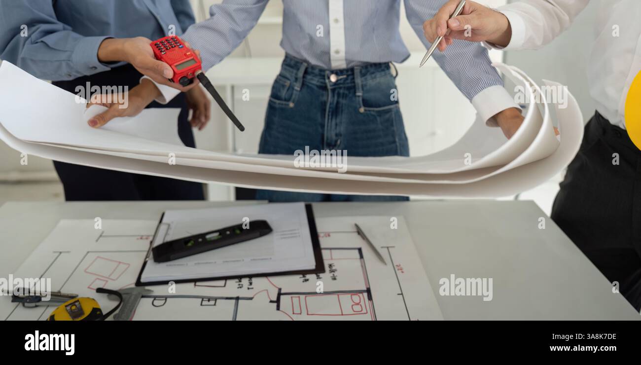 Teamwork and Project Discussion. Professionals examining detailed construction plans while focused on efficient building design. Stock Photo