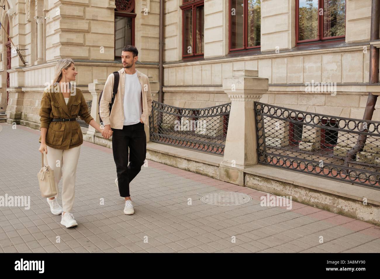 Happy couple walking hand in hand along historic city street Stock ...
