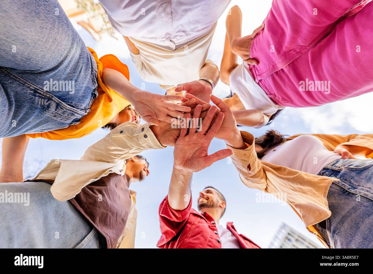 Multiracial happy friends stacking hands Stock Photo
