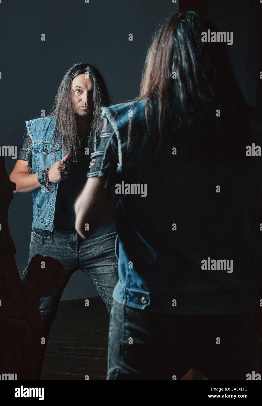 Handsome young rocker (headbanger) looking in the mirror. Portrait of ...