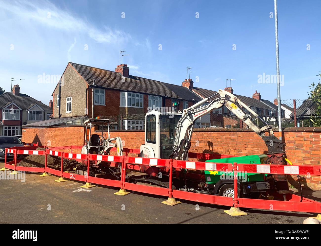 Road works in Northampton England UK Gas leak leaking dig digger wall house houses sign bollard bollards local place parked mini convertible hole in - Smartphone Captured Stock Image