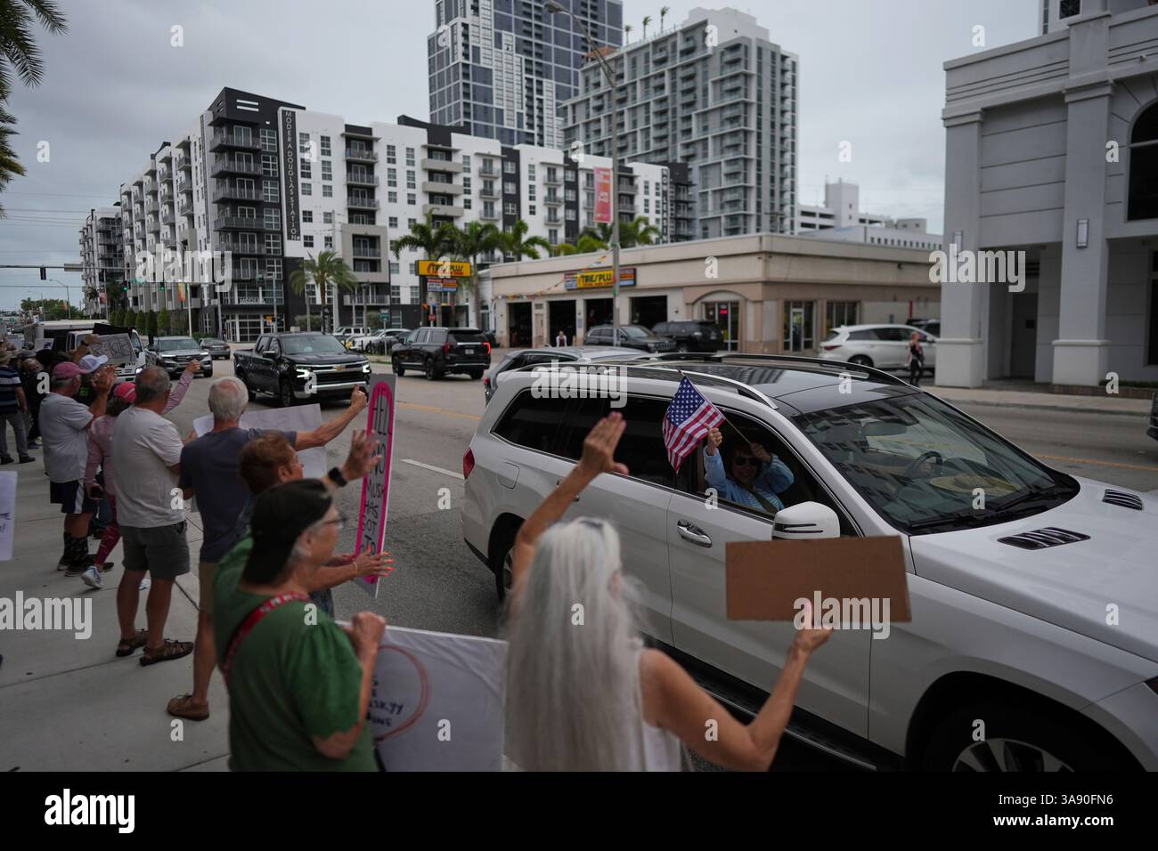 A passing driver gives a thumbs up to people protesting outside a Tesla ...