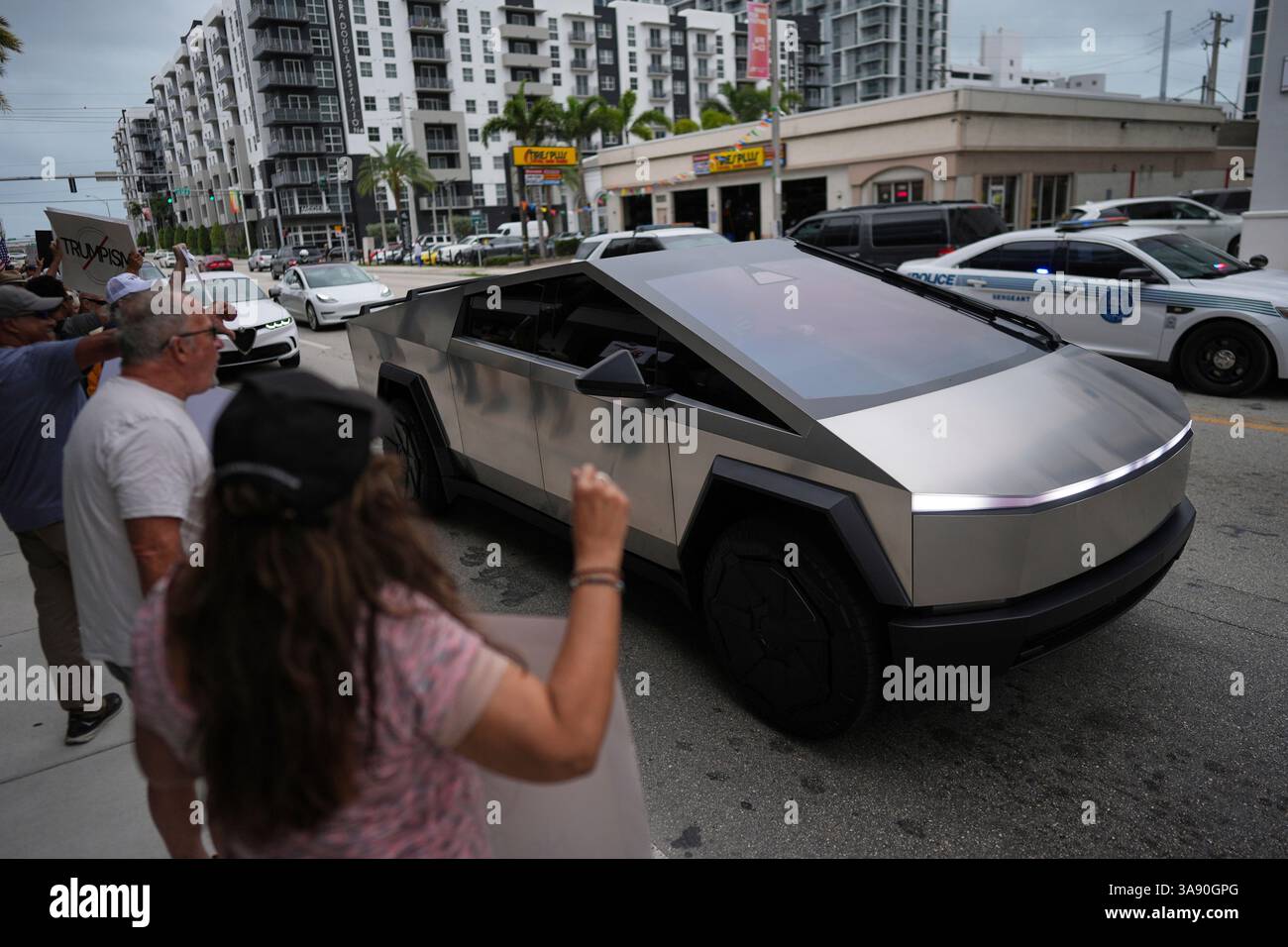 A Tesla Cybertruck drives past people protesting outside a Tesla ...