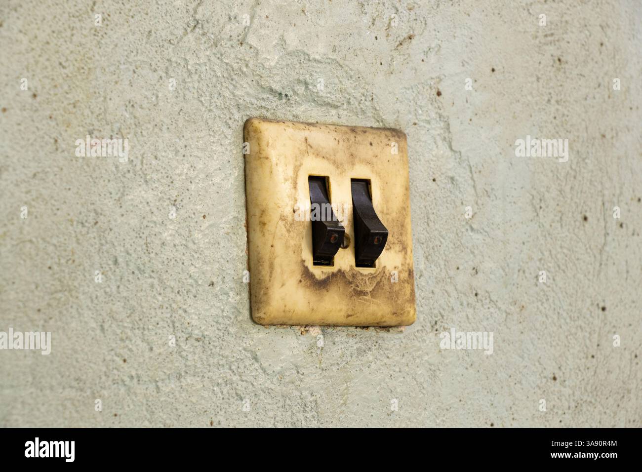 Old dirty double switch on old wall in workshop, wall switch Stock Photo