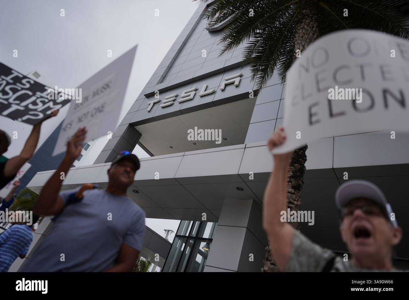 People protest in front of a Tesla dealership as part of a coordinated ...