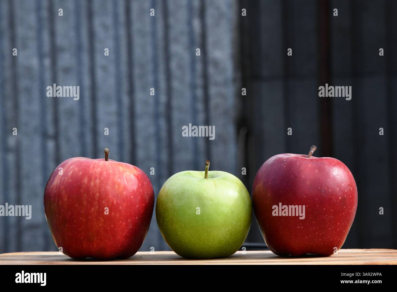 3 or three yellow apples on a clay plate isolated on a wooden background Stock Photo