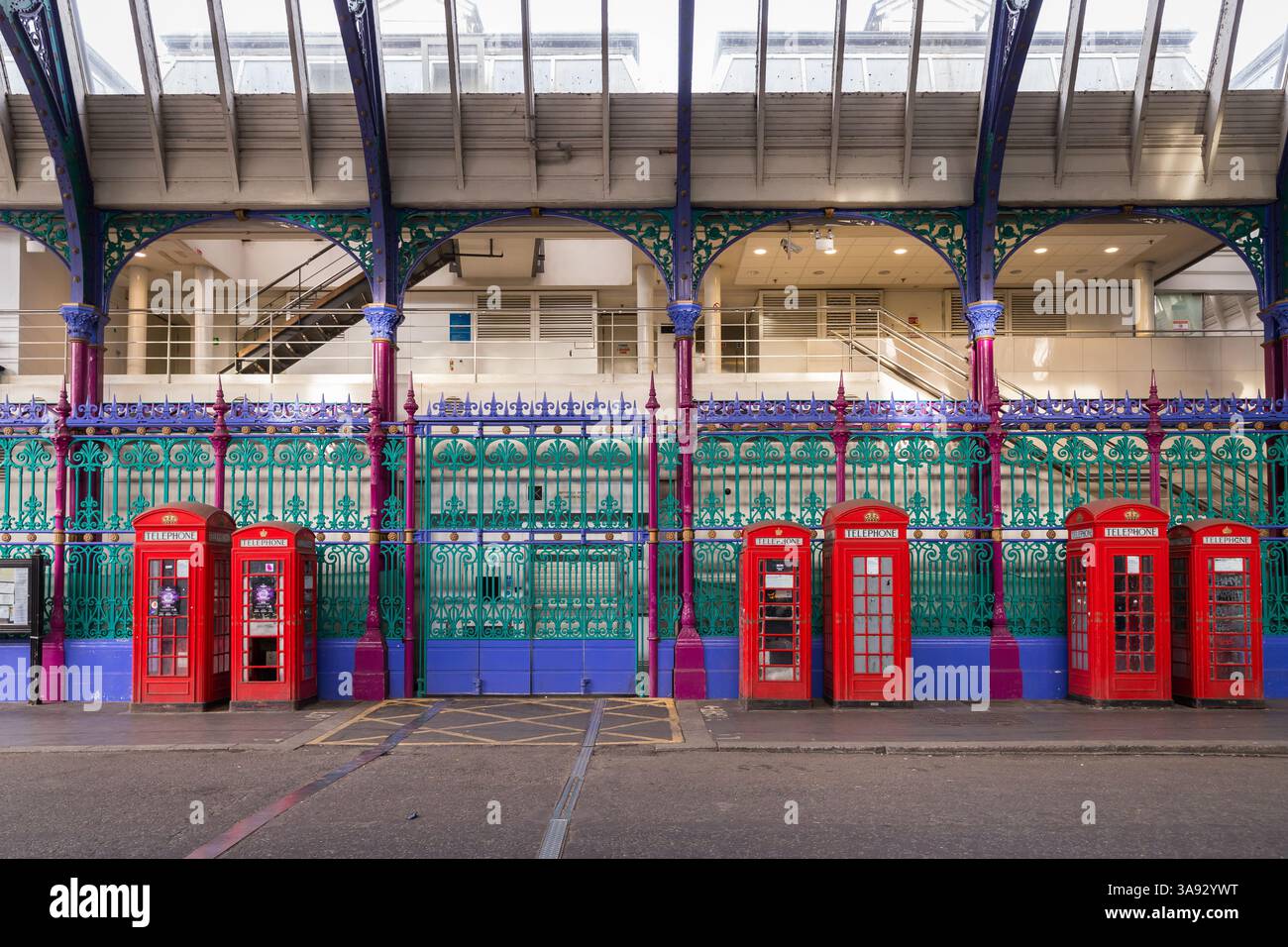 Red phone boxes next to the colourful fence of Smithfield Market Stock Photo