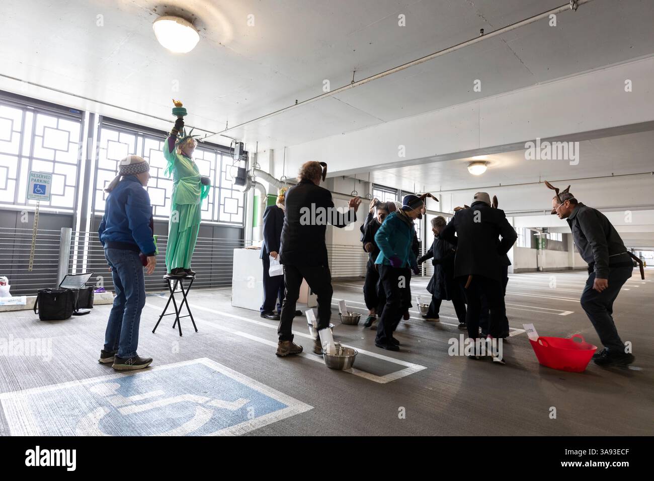Seattle, Washington, USA. 29th March, 2025. A group of self-professed “Seattle troublemakers” rehearse a skit for a rally in a University Village parking garage. The Tesla Takedown Rally, part of a Global Day of Action, is a protest against Elon Musk and the Donald Trump administration. Credit: Paul Christian Gordon/Alamy Live News Stock Photo
