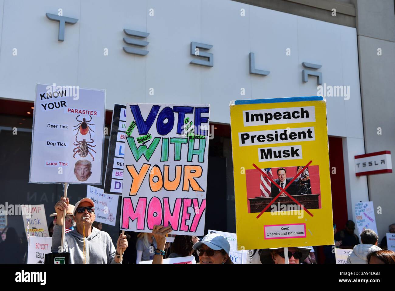 Protesters hold signs in front of a Tesla dealership in Walnut Creek ...