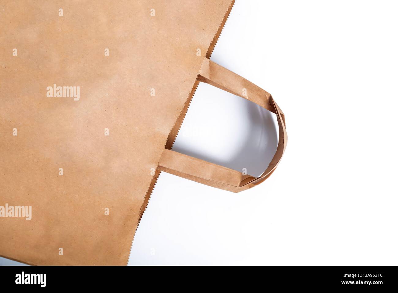 A brown paper bag with sturdy handles placed on a white background. Perfect for packaging, shopping, or environmental presentation. Stock Photo