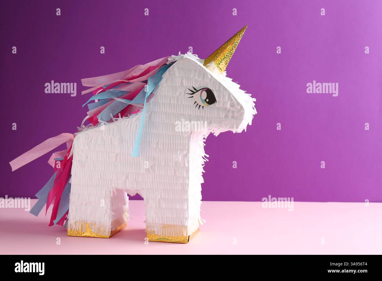 Bright pinata in shape of unicorn on color background, space for text ...