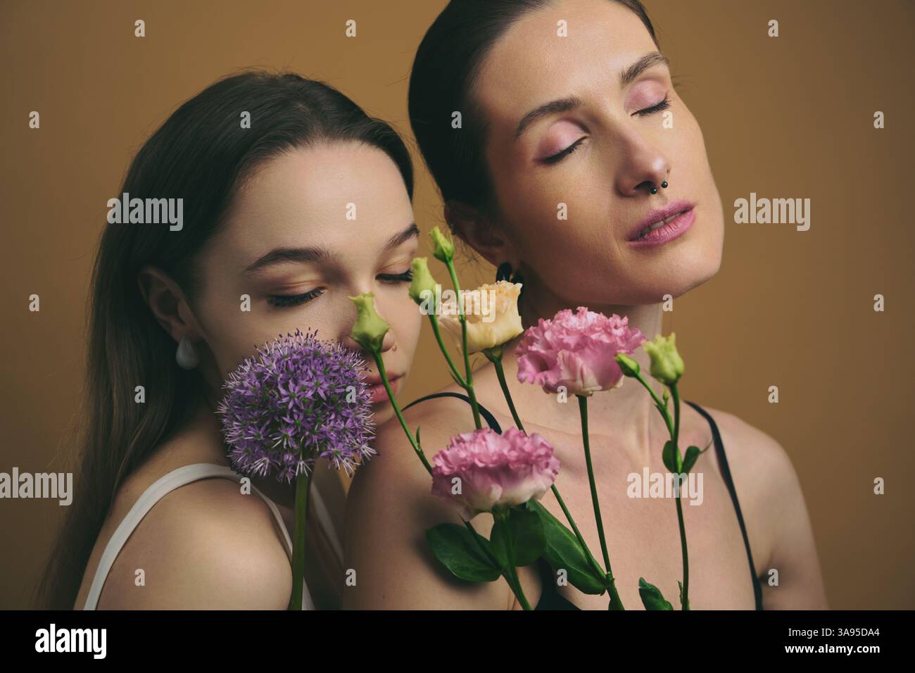 Two women posing with flowers in a studio setting Stock Photo - Alamy
